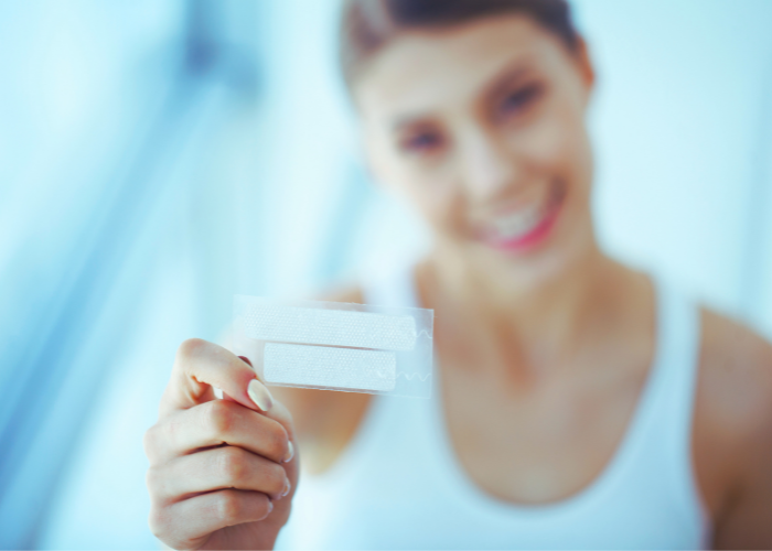 Smiling person holding whitening strips
